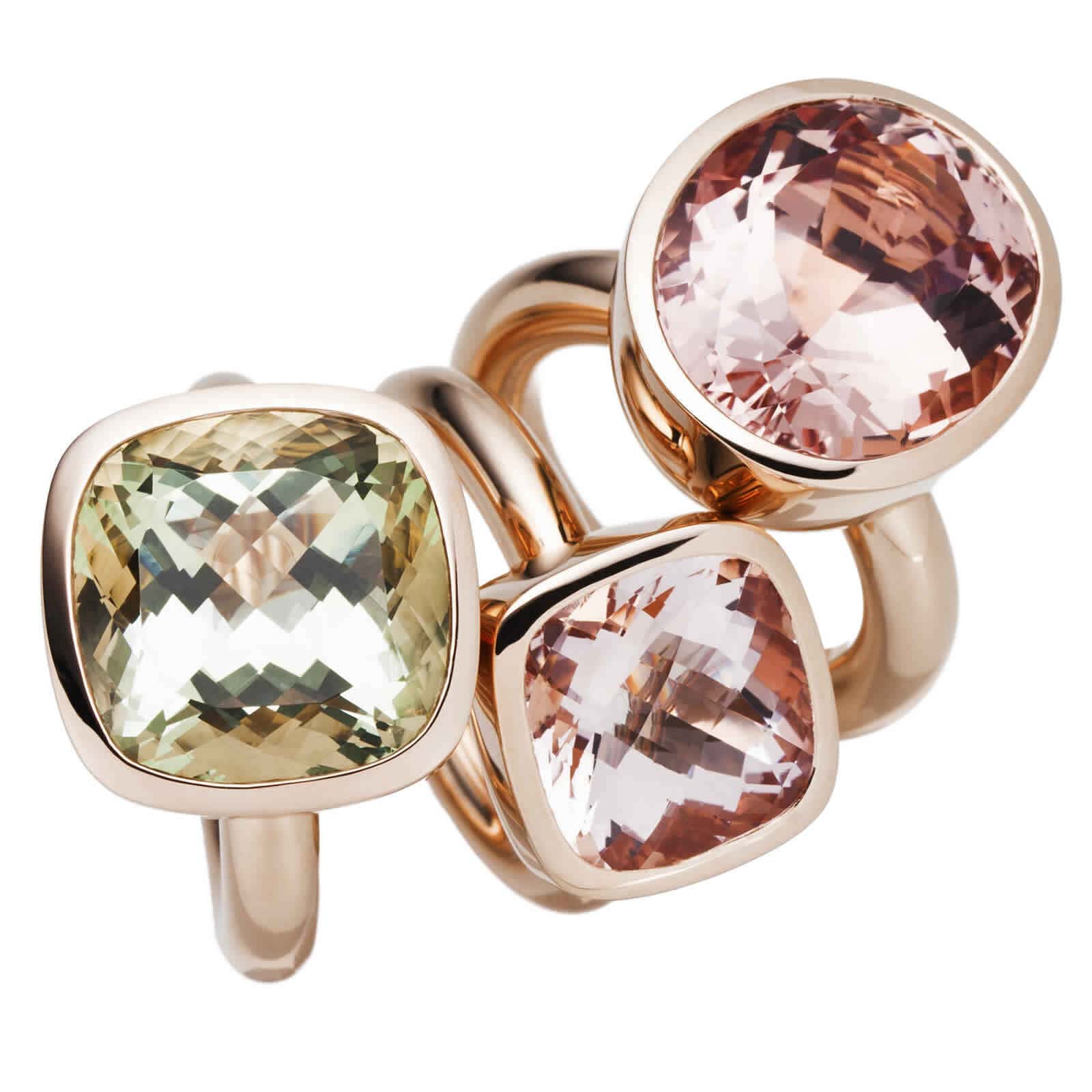Drei Ringe in Roségold mit unterschiedlichen quadratischen Steinen in verschiedenen Farben.